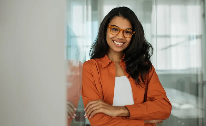 Portrait of smiling business woman wearing stylish eyeglasses looking at camera standing in modern office.