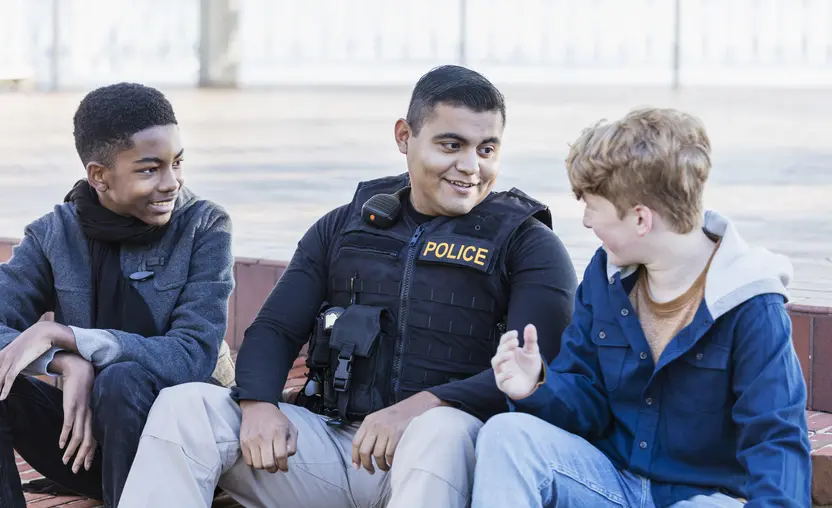 A police officer sits between two young people.