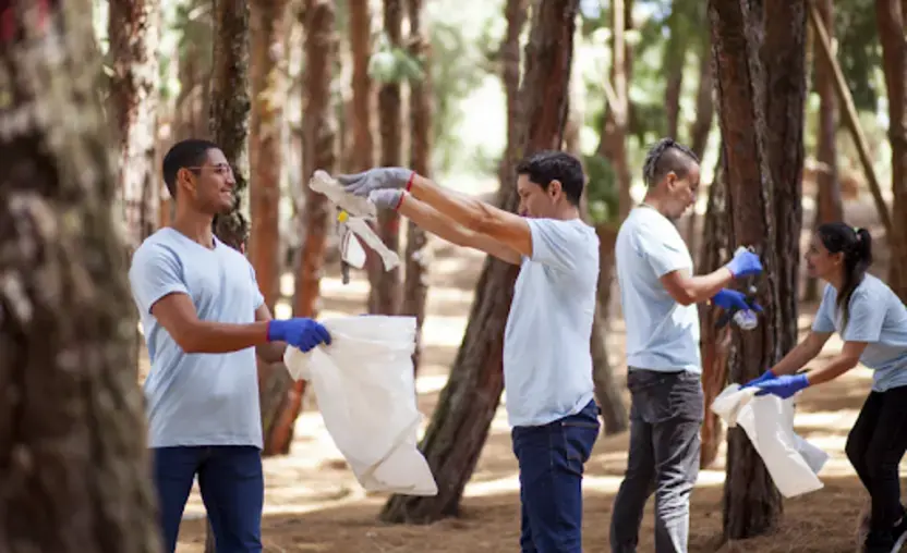 Four employees pick up trash at a volunteer event while participating in an employee giving program.