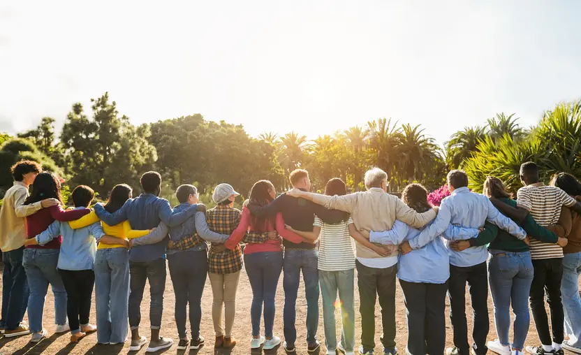 Group of people standing outside with their arms around each other.