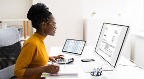 A woman does calculations on a calculator as part of her grant management and accounting work.