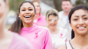 women smile while running in support of breast cancer research. They are cultivating giving tuesday success by wearing pink clothing with breast cancer awareness ribbons.