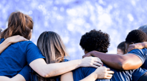 Catholic Social Services workers stand together with arms over each other's shoulders