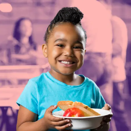 Girl smiling at the camera holding a bowl of food