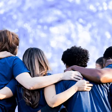 Catholic Social Services workers stand together with arms over each other's shoulders