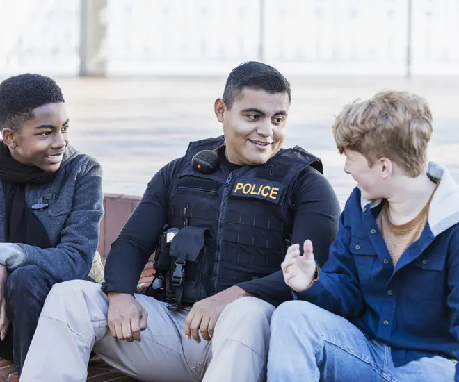 A police officer sits between two young people.