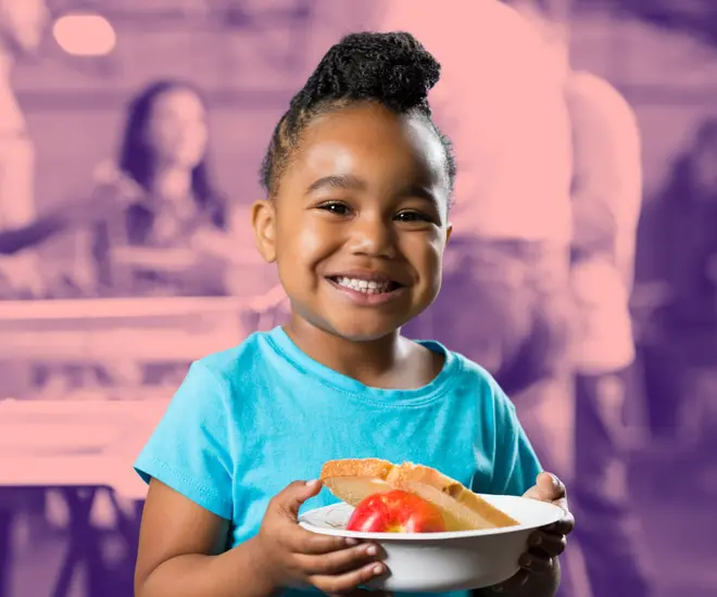 Girl smiling at the camera holding a bowl of food