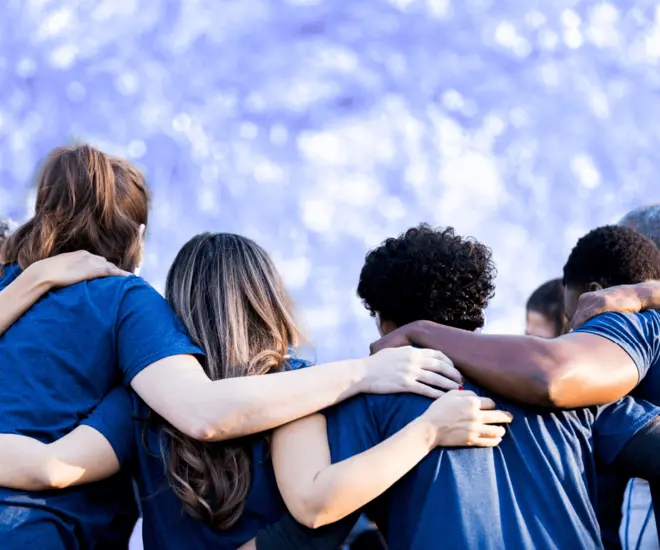 Catholic Social Services workers stand together with arms over each other's shoulders