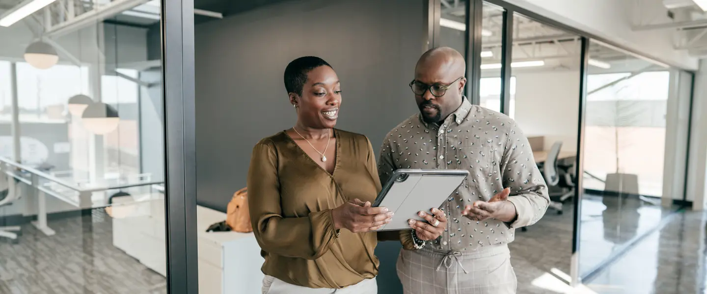 Two nonprofit professionals stand and look over a waiver to ensure that it covers all the nonprofit waiver essentials.