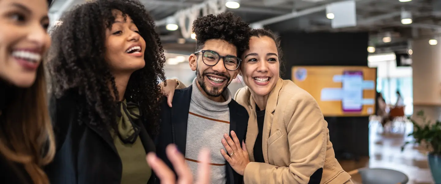 A diverse group of workers embrace and talk at the office, showing the importance of supporting and investing in BILPOC nonprofit leaders.