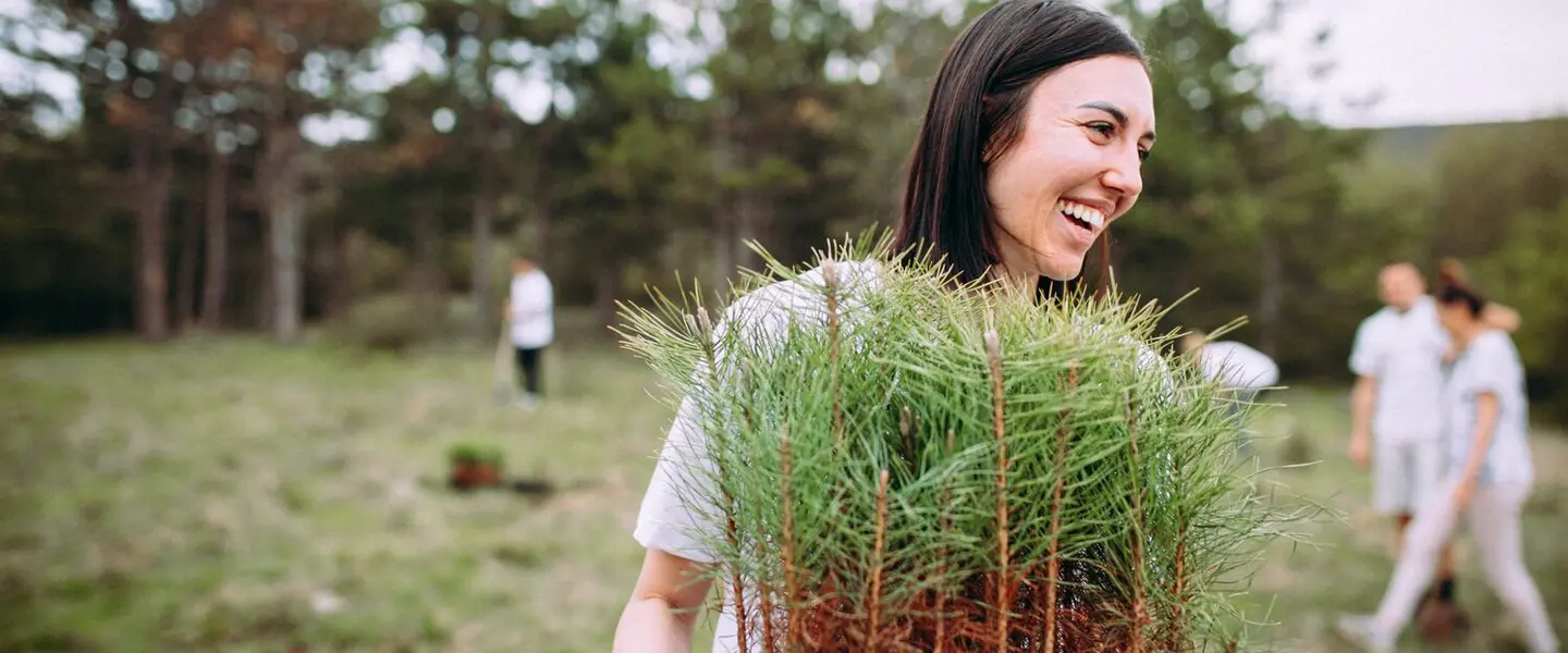 A female volunteer carrying trees to be planted at the service site. 