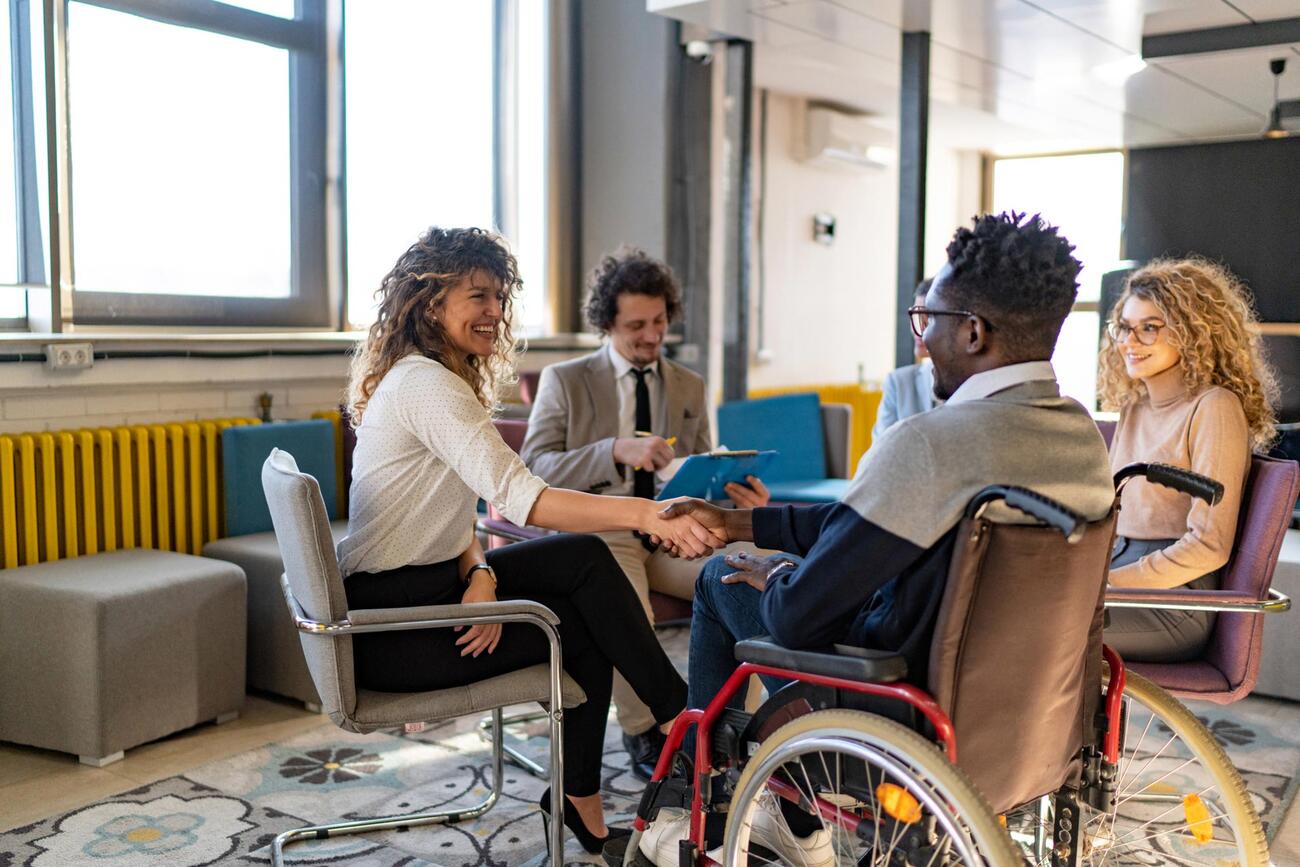 Two people shake hands as they start a group meeting