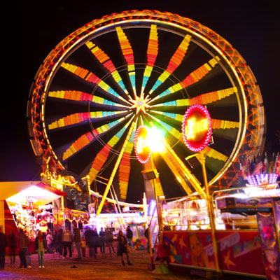 This photo of a lighted Ferris wheel at night shows an example of the campus carnival fundraising event idea for sororities and fraternities.