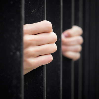 This photo of hands gripping cell bars represents the creative and unique, jail and bail fundraising event idea.