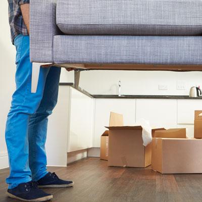 This photo of someone moving a sofa into a room filled with moving boxes could show a fundraising event idea for sports teams.