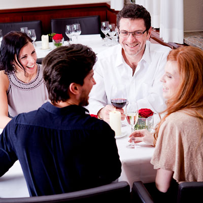 This photo of young professionals having dinner and chatting shows the effectiveness of an alumni networking dinner as a fundraising event idea.