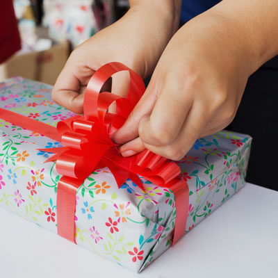 This photo of a gift being wrapped shows the concept of the wreaths and wrapping fundraising event idea for faith-based organizations.