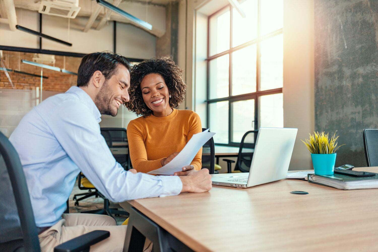 Two young businesspeople reviewing documents in an office.