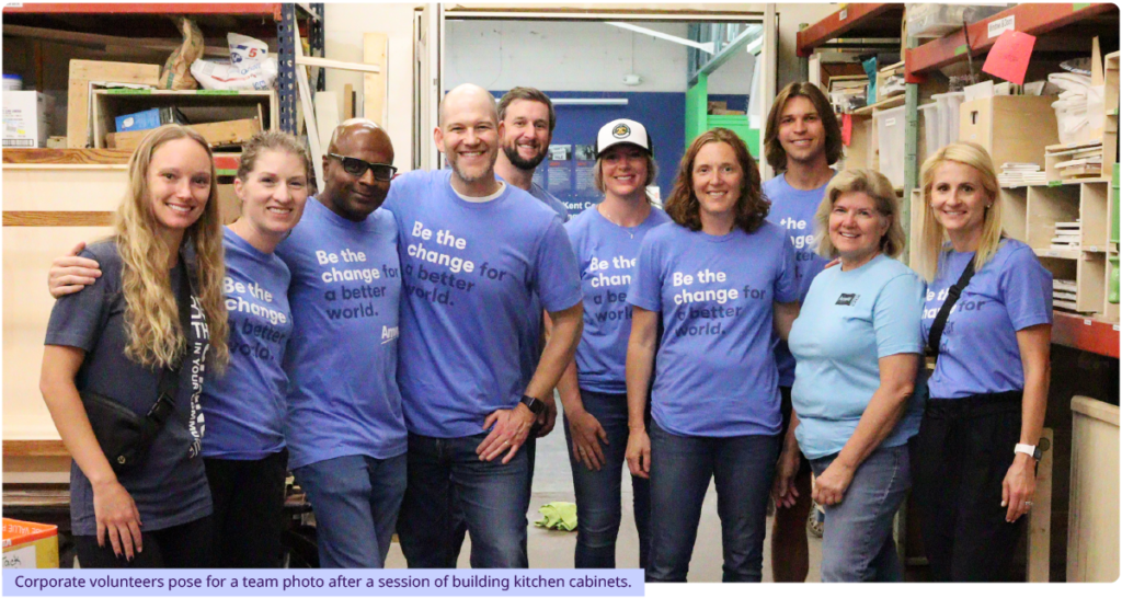 Corporate volunteers pose for a team photo after a session of building kitchen cabinets.