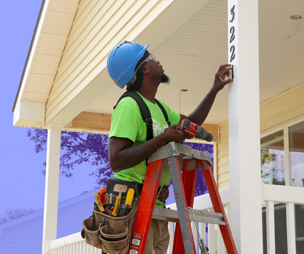 Habitat for Humanity volunteer hanging house numbers on a column