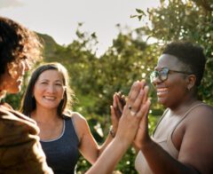 A group of women celebrate with high-fives outdoors.