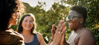 A group of women celebrate with high-fives outdoors.