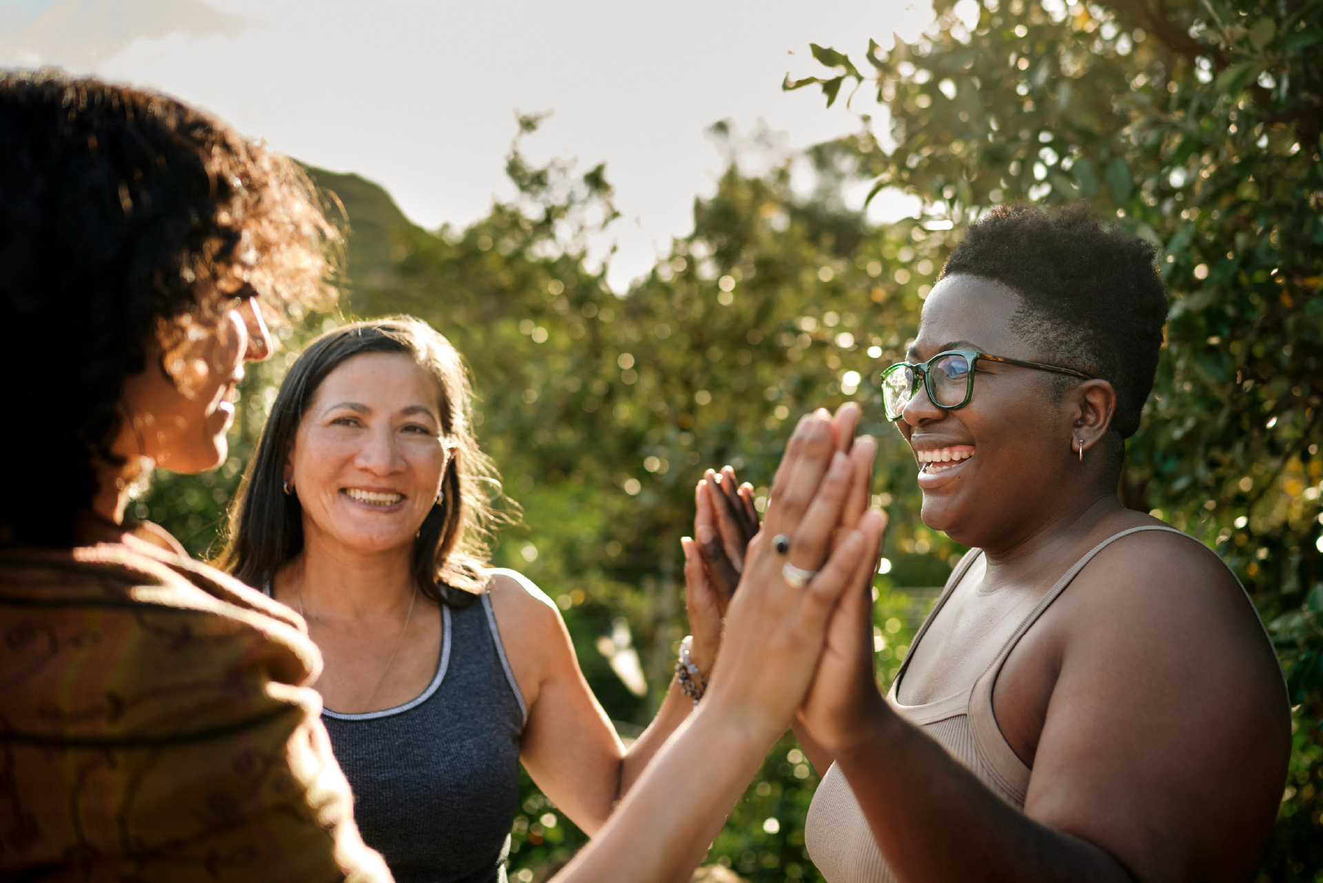 A group of women celebrate with high-fives outdoors.