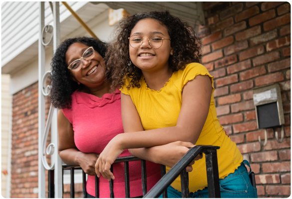 Family looks to the camera in front of their house