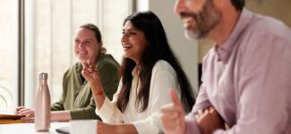 Businesspeople laugh as they engage with a presentation.