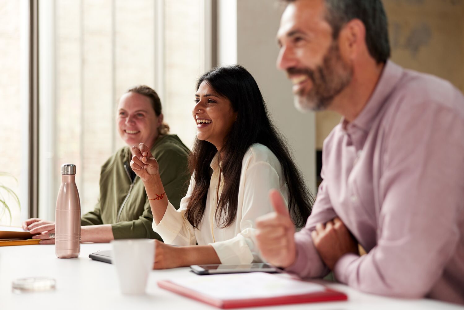 Businesspeople laugh as they engage with a presentation.