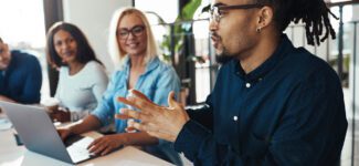 Coworkers meet and have a discussion in front of a laptop