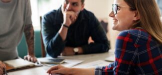 Three coworkers gathered around a table discussing their nonprofit case management platform