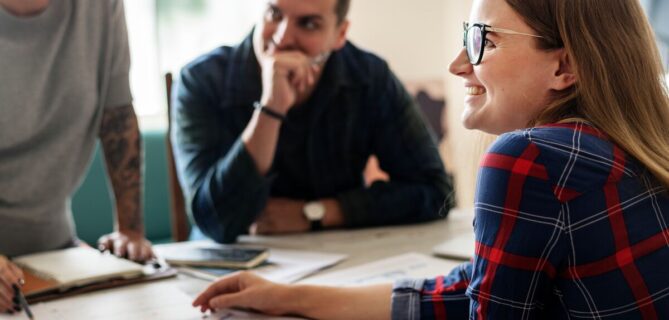 Three coworkers gathered around a table discussing their nonprofit case management platform