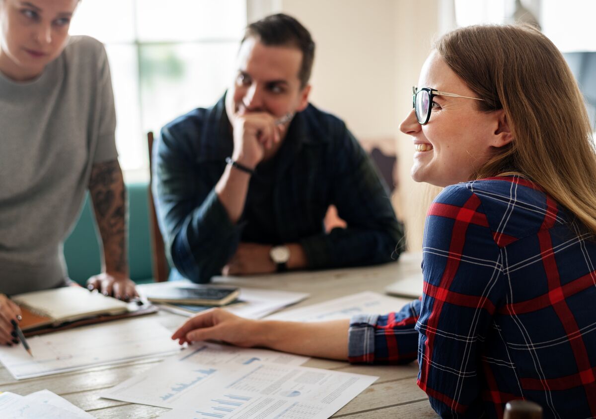 Three coworkers gathered around a table discussing their nonprofit case management platform