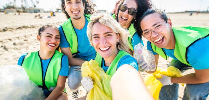 A group of employees works together to clean up a local shoreline.