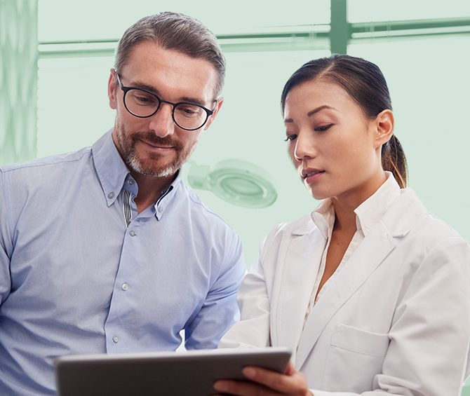 Two healthcare professionals review data on a tablet.